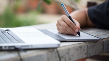 Graphic designer using digital tablet and computer at home office