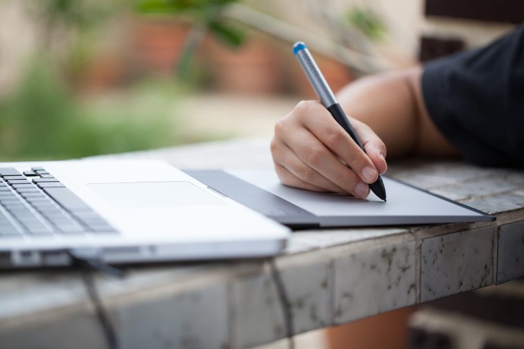 Graphic designer using digital tablet and computer at home office