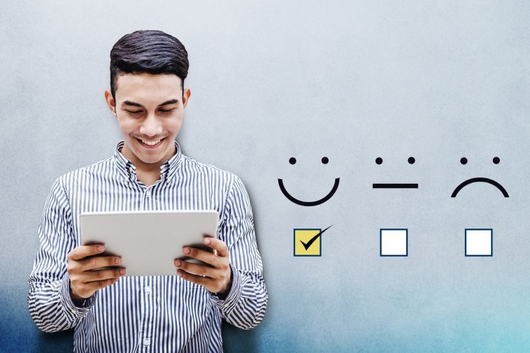 Customer Experience Concept, Happy Businessman holding digital Tablet with a checked box on Excellent Smiley Face Rating for a Satisfaction Survey
